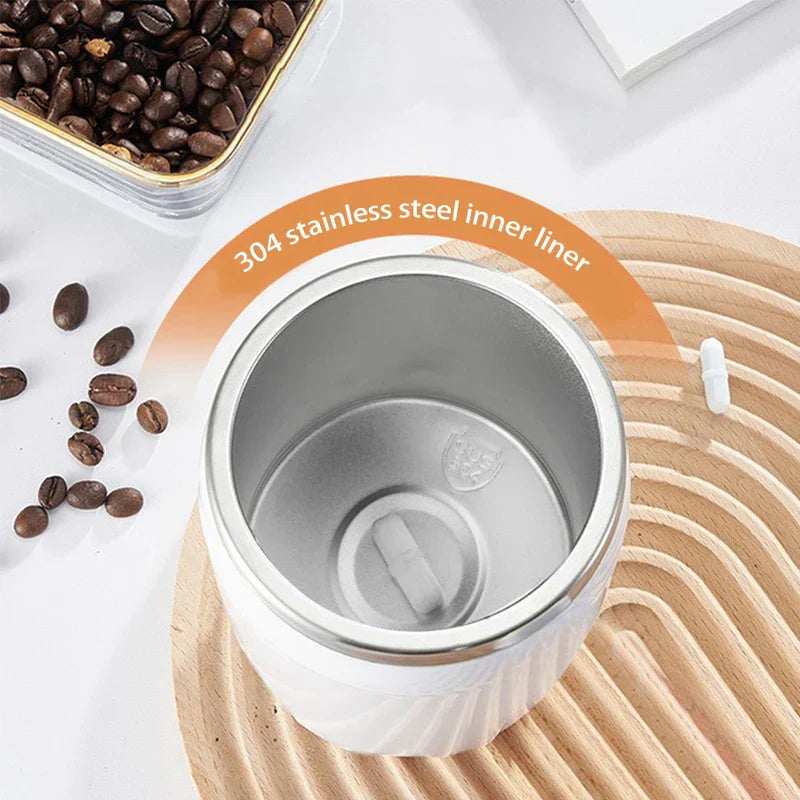 Automatic Mixing Mug Cup - Top-down view of a white cup with 304 stainless steel interior, placed on a wooden mat with coffee beans nearby