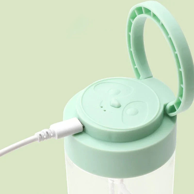 Automatic Mixing Mug - Close-up of a mint green electric blender cup lid with a USB charging cable plugged in, flip-up carry ring open, and panda face embossed on top