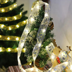 Battery Box - Lit silver star LED ribbon string light draped beside small flocked Christmas tree and wooden reindeer decor