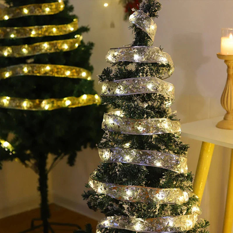Battery Box - Lit silver LED ribbon string light wrapped around small flocked Christmas tree with larger tree in background