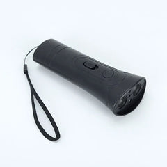 Dog Training Clicker - Black handheld device with attached black wrist lanyard, laid on a plain white surface