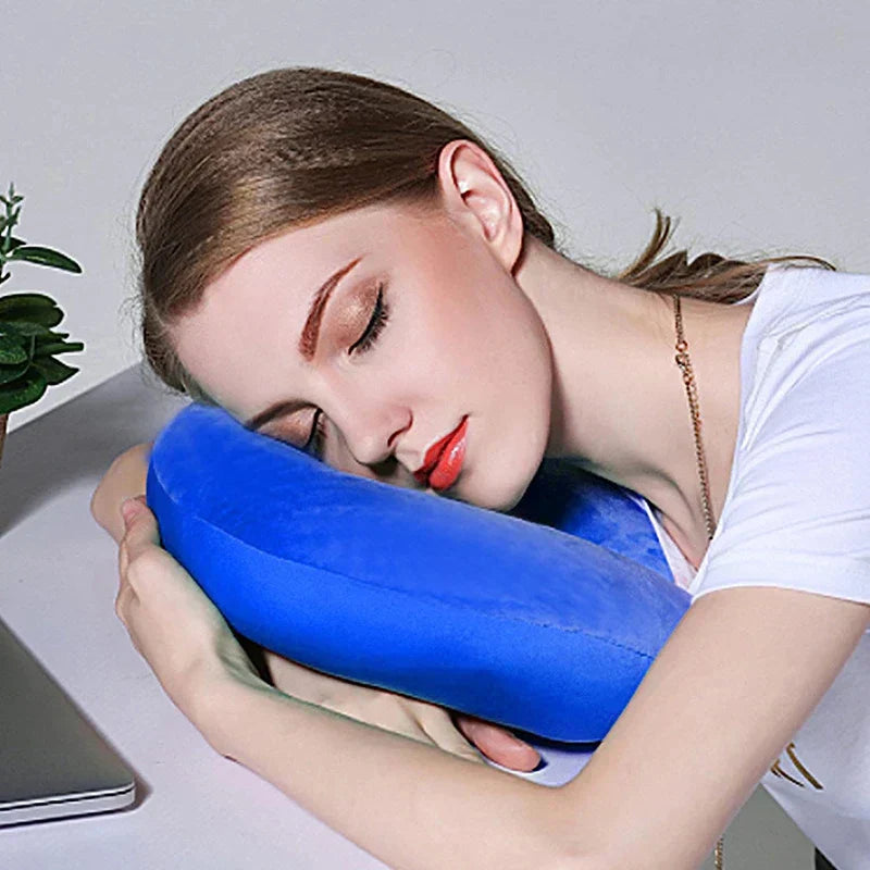 Woman resting her head on a blue U-shaped massage pillow at a desk