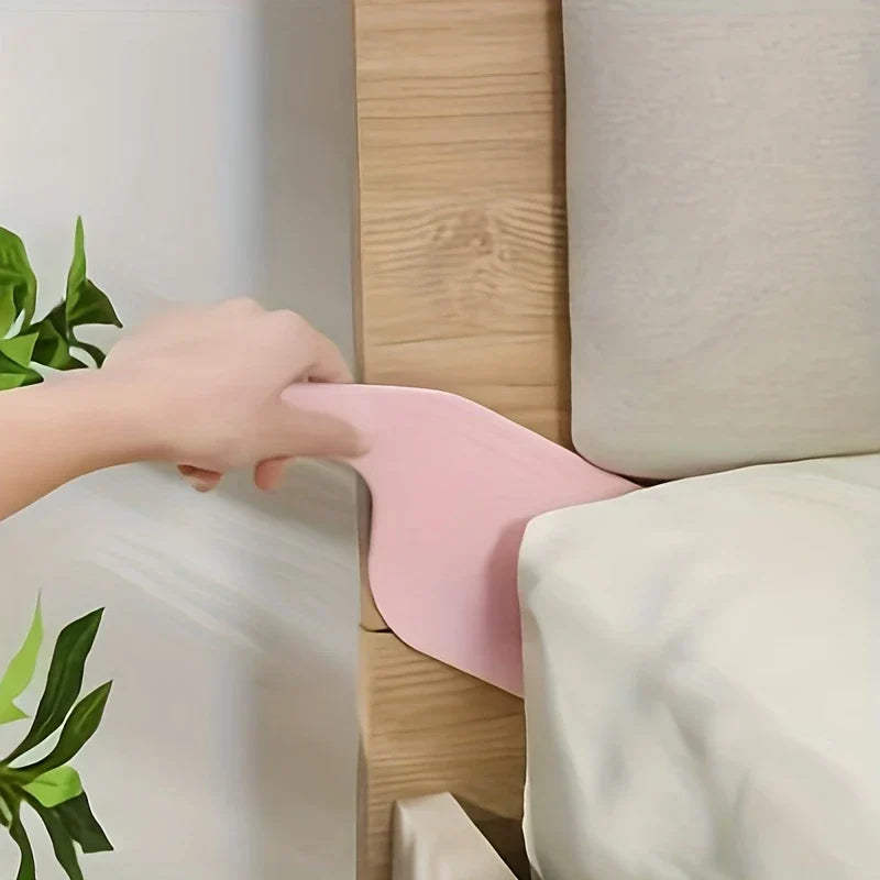 matratzenheber paddel - Hand führt rosa Paddel-Werkzeug zwischen Matratze und hölzernem Bettrahmen nahe dem Kopfteil ein