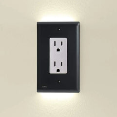 An outlet cover with integrated led night guidelight is shown mounted on a light beige wall, with soft LED light glowing from its top and bottom edges.