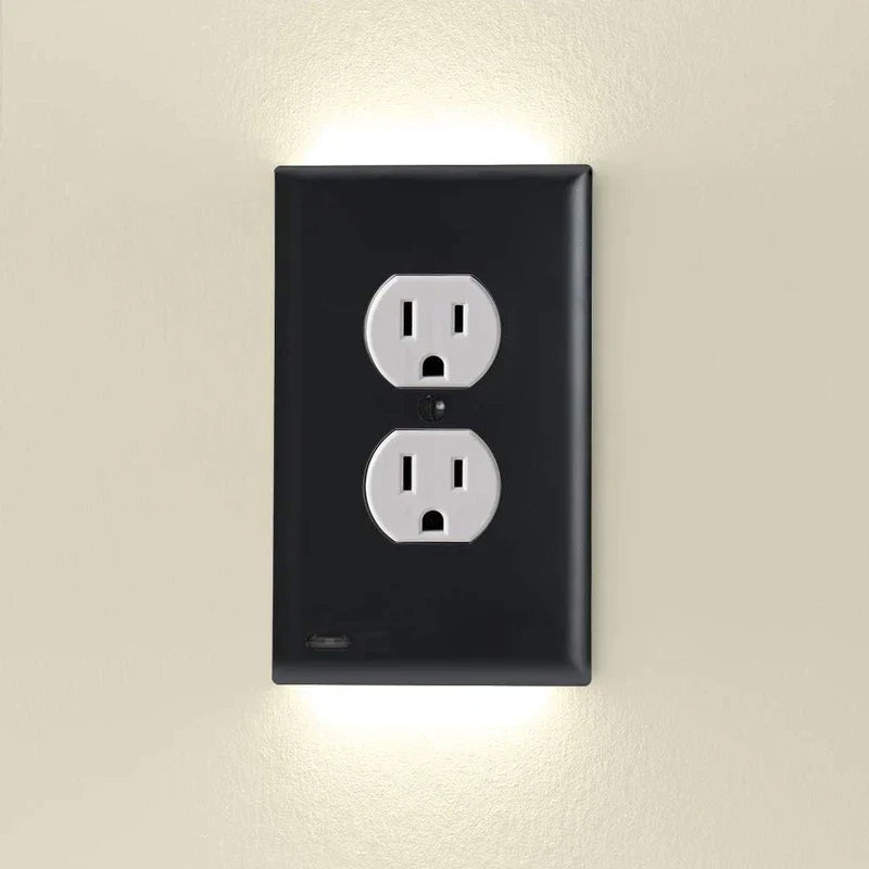 A black outlet cover with integrated led night guidelight mounted on a wall, with soft led light glowing above and below.