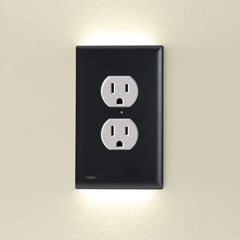 A black outlet cover with integrated led night guidelight mounted on a wall, with soft led light glowing above and below.