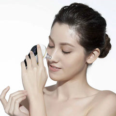 Pore Cleaner - A woman with dark hair in a bun uses a small white facial device with a clear tip on her nose, eyes closed.