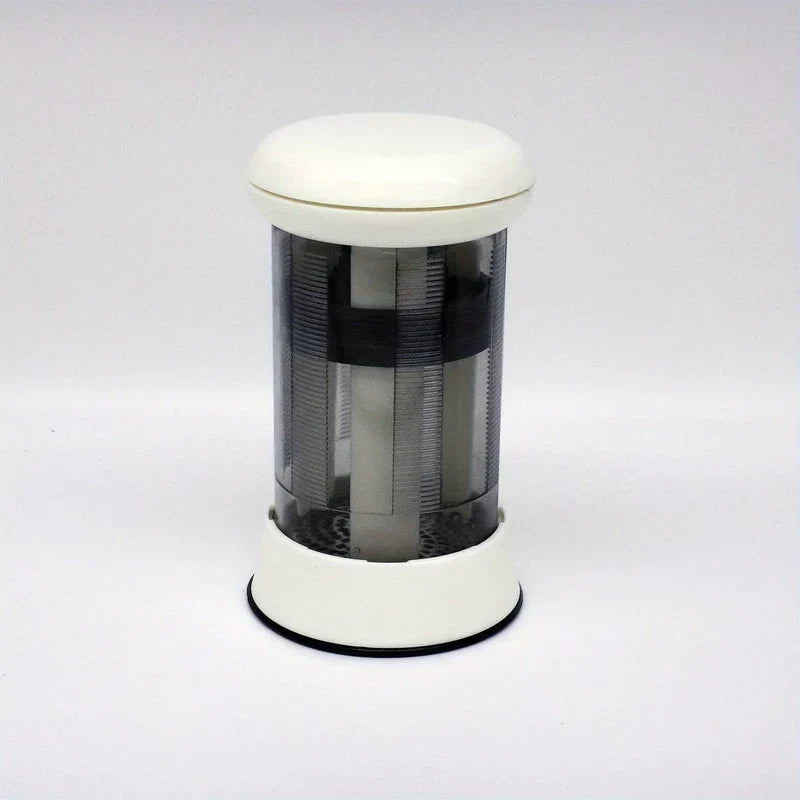 Butter Grater - white and clear cylindrical mill dispenser standing on plain light gray background