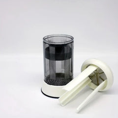 Butter Grater - Cylindrical device with detached white top piece leaning against its translucent body with white base on a white surface