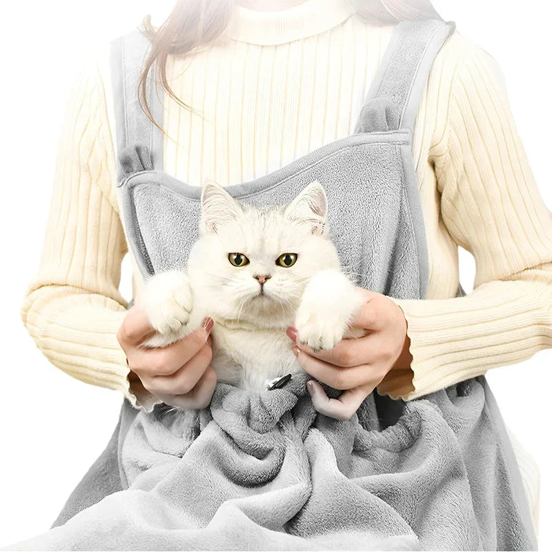 Delantal portabebés para gato con bolsillo acogedor - Una persona con un suéter de canalé color crema sostiene un gato blanco descansando dentro de un portabebés delantero suave estilo delantal gris, con un cordón en la parte frontal del portabebés