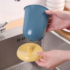 Soporte cerámico para palillos, escurridor y organizador de cubiertos - Dos manos separan un vaso organizador azul de su base amarilla, mostrando el poste central elevado de la base, sobre un fregadero.