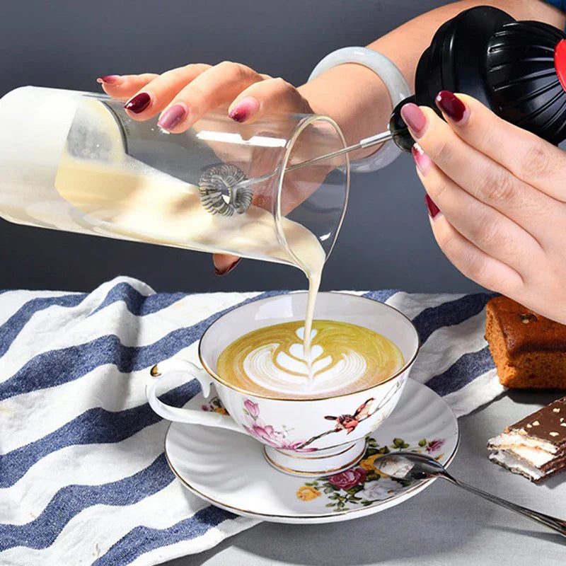 Coffee Drink Stirrer Electric Foaming Tool - Foamed milk being poured from glass foamer carafe into floral latte cup with heart art