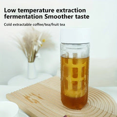 Cold Brew Coffee Maker - Clear cold brew bottle with white lid holds amber liquid inside, placed on wooden mat, text 'Low temperature extraction' above