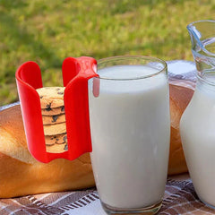 soporte expositor para galletas y bizcochos con rejilla - Soporte rojo para galletas enganchado a un vaso de leche, sosteniendo galletas con chispas de chocolate apiladas, colocado sobre una manta de picnic al aire libre