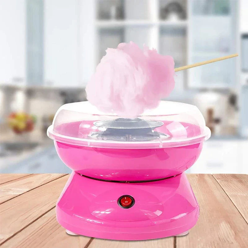 Floss Maker - Pink cotton candy machine on wooden kitchen counter with freshly spun pink cotton candy on a stick