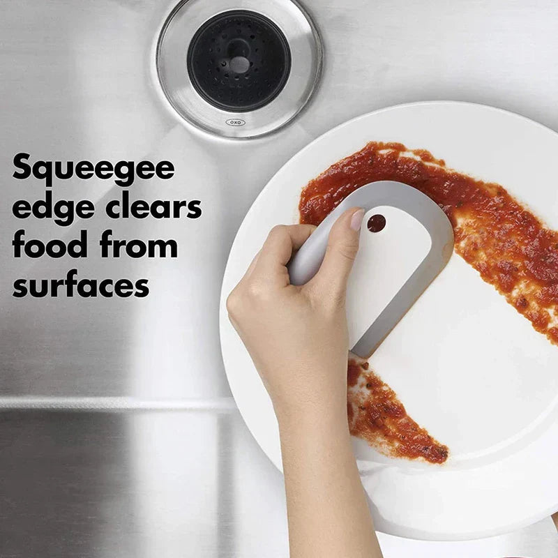 Countertop Dishwasher Machine - hand using squeegee edge tool to scrape red sauce from a white plate over sink