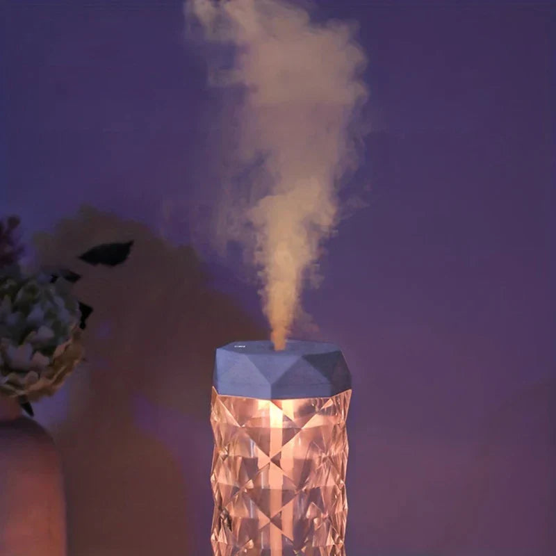 Night Light - Crystal-cut humidifier emitting warm-hued mist, lit warm amber, with a flower arrangement partially visible to the left.
