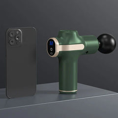Massage Gun - Green compact handheld massager next to a smartphone to show portable size, with digital speed display showing 32