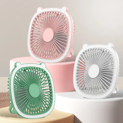 Three pastel-colored small fans (pink, green, white) with ear accents displayed on tiered platforms