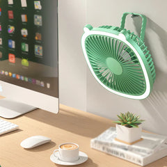 Green fan with top hanging strap mounted on a wall beside a desktop computer and office items
