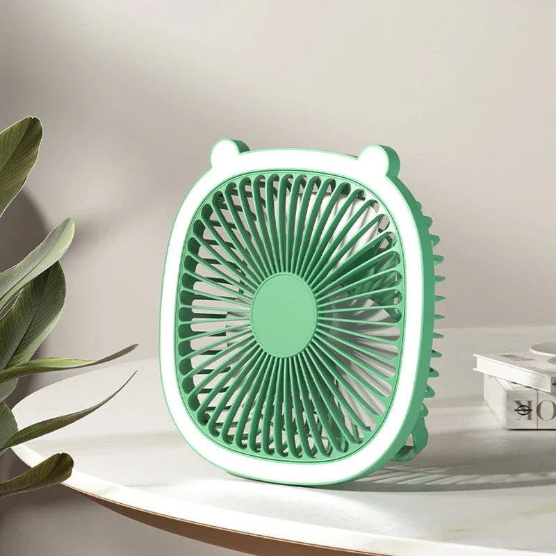 Mint green desktop desk lamp with cooling fan sits on a white marble table with green foliage nearby
