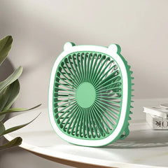Mint green desktop desk lamp with cooling fan sits on a white marble table with green foliage nearby
