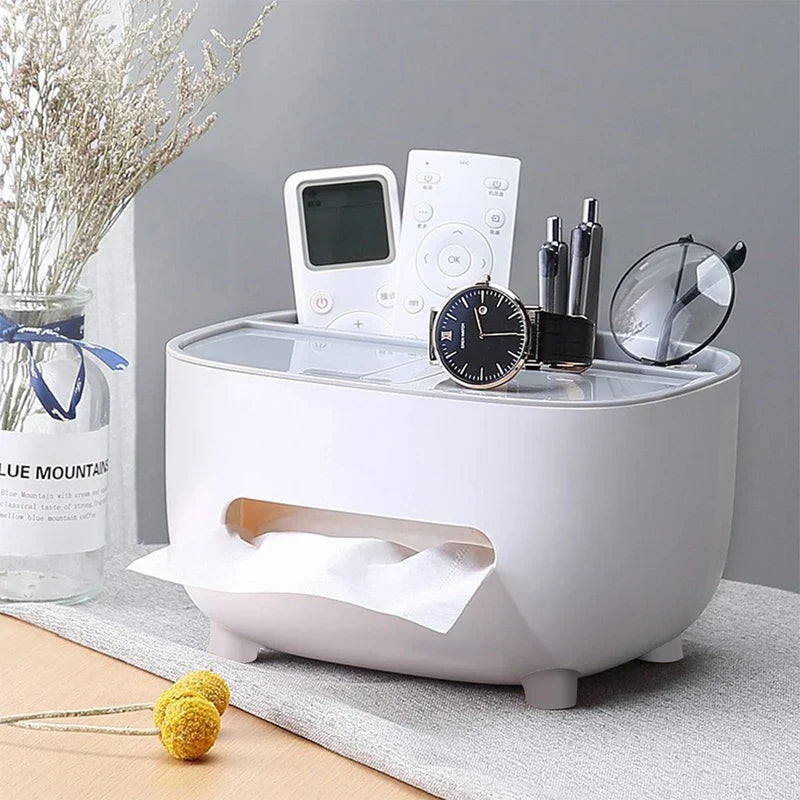 A desktop organizer shelf with tissue box holder holds a watch, remotes, pens, and glasses on top, with a tissue protruding from its front slot.