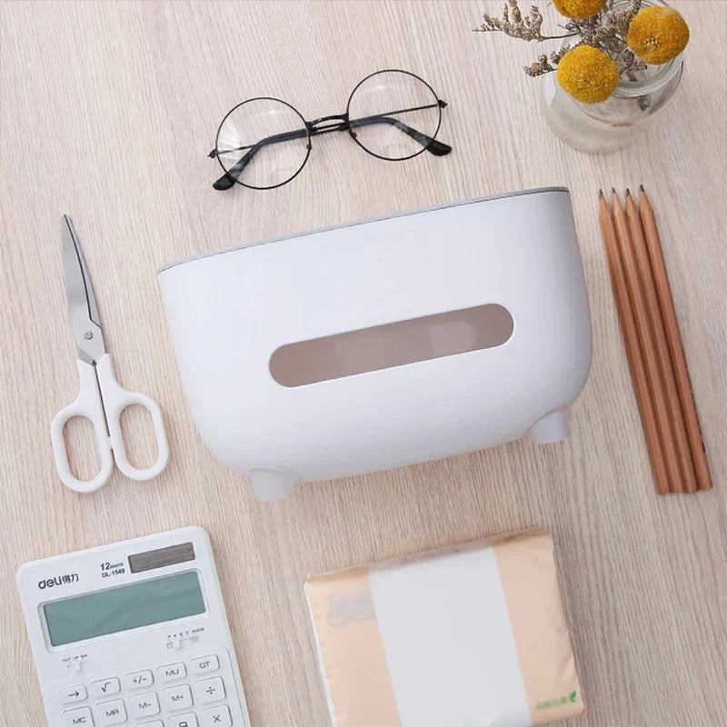 A desktop organizer shelf with tissue box holder sits on a light wood desk alongside scissors, eyeglasses, pencils, a calculator, and a tissue pack.