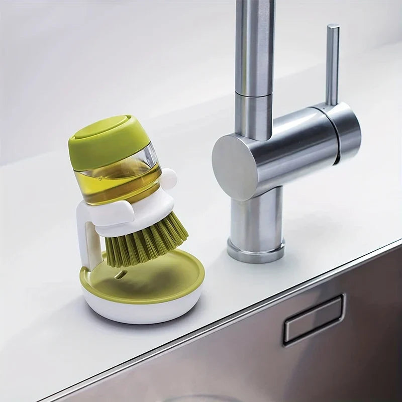 Brosse à vaisselle - Brosse de nettoyage avec distributeur de savon reposant dans son support à côté d'un robinet de cuisine en acier inoxydable sur un comptoir d'évier blanc
