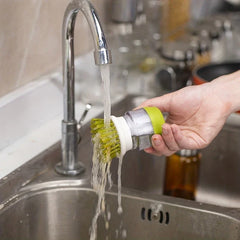 Dish Brush - A hand holds the soap dispensing brush under running faucet water to rinse it over a kitchen sink.