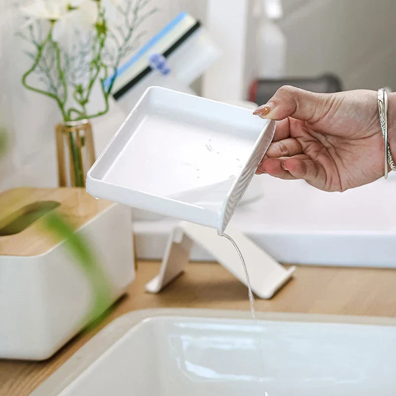 Soap Dish Holder - Hand tilting a soap tray to pour out collected water over a bathroom sink.