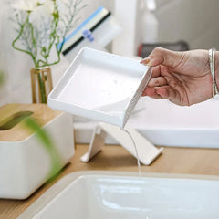 Soap Dish Holder - Hand tilting a soap tray to pour out collected water over a bathroom sink.