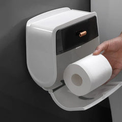 Mano insertando un rollo de papel higiénico en un portapañuelos de plástico abierto montado en la pared, instalado sobre una pared oscura