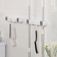 Double Mop Broom Holder - Two units mounted on a white tiled wall holding mop handles and small hanging cleaning tools
