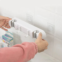 Double Mop Broom Holder - Hands holding a white mop holder aligning it to clear adhesive stick-on pads affixed to a glossy tiled wall.