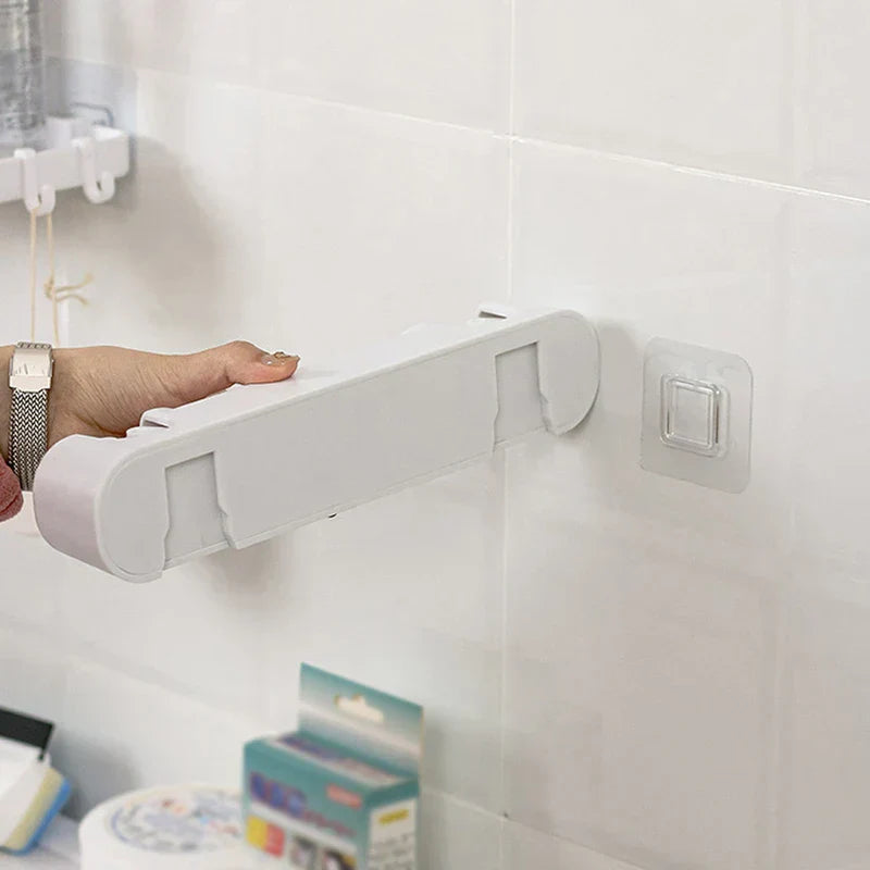 Double Mop Broom Holder - Hand installing a white wall-mounted organizer onto an adhesive hook on a white tiled wall