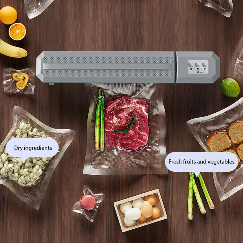 Vacuum Sealer Machine - Closed gray vacuum sealer on wood surface surrounded by vacuum-sealed dry goods, produce, meat, and loose food items