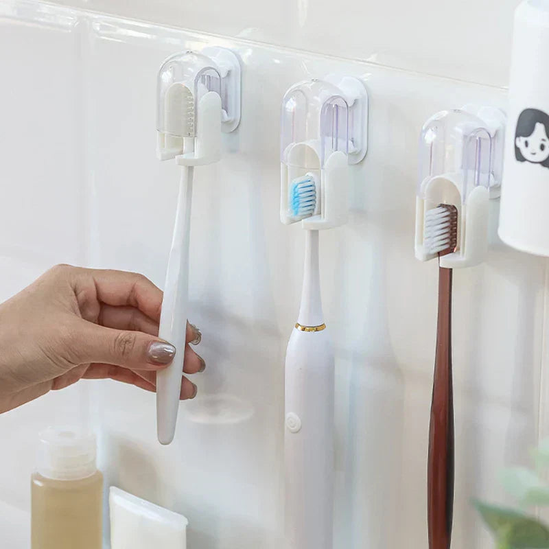 Hand placing a manual toothbrush into a wall-mounted toothbrush holder beside two other holders