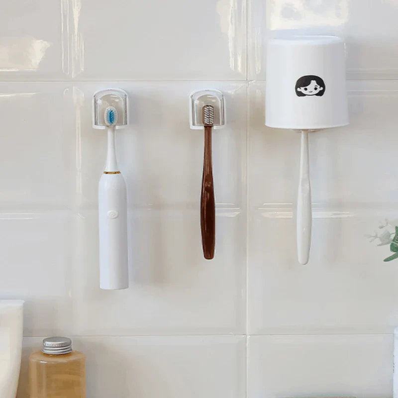 Toothbrush Holder - Wall-mounted toothbrush holders holding an electric toothbrush, a manual toothbrush, and a cup, on a white tiled bathroom wall.