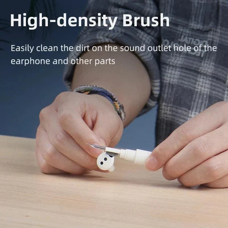 Earbuds Cleaner Kit - Hands resting on a light wooden surface hold a pen-style cleaning tool touching a white wireless earbud, with descriptive text above.