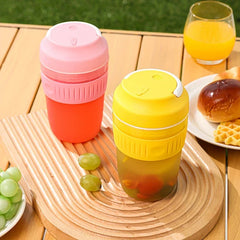 Electric Citrus Juicer - Two cups (one pink and red, one yellow) sit on a wooden tray with grapes, bread and a glass of orange juice on an outdoor wooden table