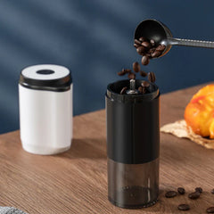 Electric Coffee Bean Grinder - Coffee beans being poured from a scoop into the open grinder, with the grinder's white upper motor section placed nearby on a wooden surface.