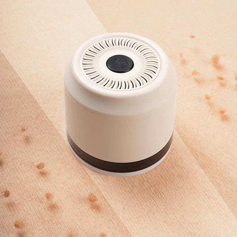 Lint Remover - White fabric shaver resting on light beige fabric with scattered lint balls beside it