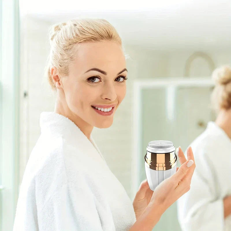 Facial Cleansing Spin Brush - Smiling woman in a white bathrobe holding the white and gold facial cleansing brush in a bright bathroom, mirror reflection in background