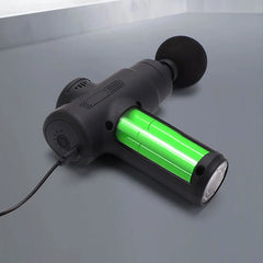 Electric Fascia Vibration Recovery Gun - Black mini massage gun plugged in charging, with flat massage head attached and green illuminated battery indicator
