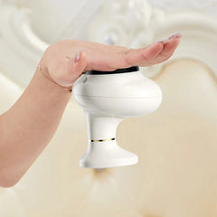 Electric Gua Sha Tool - Hand holding the white handheld device palm-down against a light neutral background
