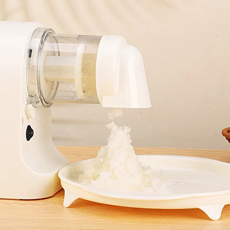 Ice Shaver Machine - Close-up of the white electric appliance producing shaved white ice onto a white footed tray on a wooden surface