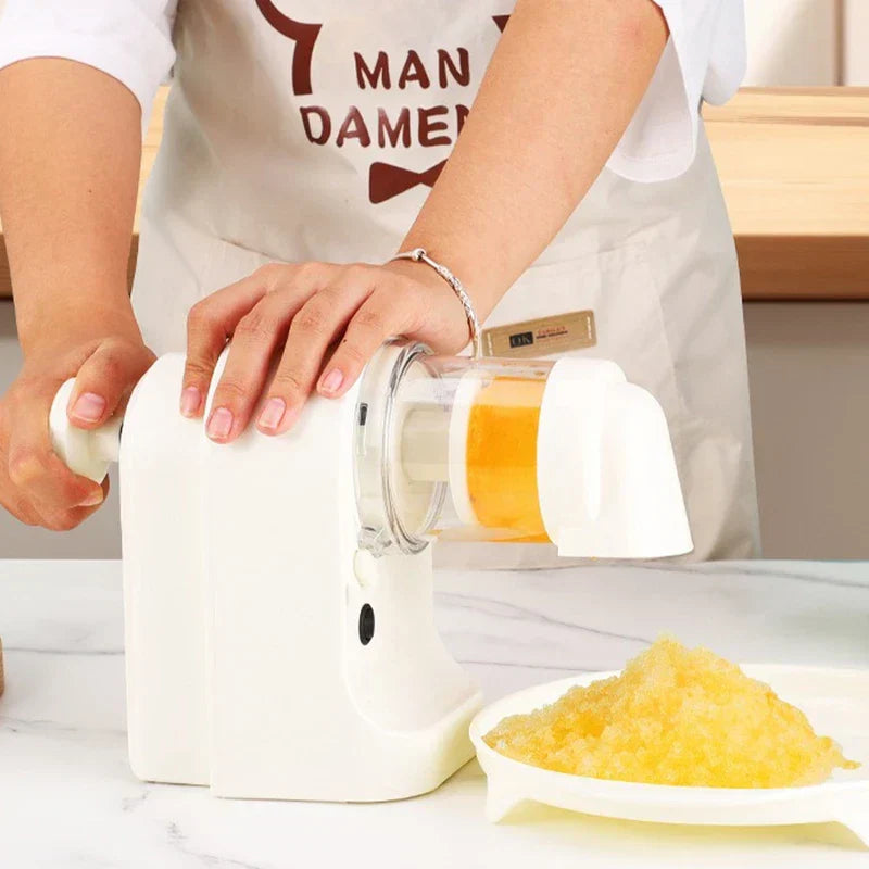 A person turns the side handle of an ice shaver machine, producing yellow shaved ice in a dish