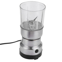 Coffee Spice Grinder - Angled view of stainless steel electric grinder with transparent grinding bowl, visible internal blades, power cord extending from the base, set on a plain white background