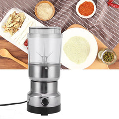 Coffee Spice Grinder - Front view of an upright electric grinder with stainless steel body and clear grinding cup, placed on a wooden surface surrounded by various whole and ground food ingredients.